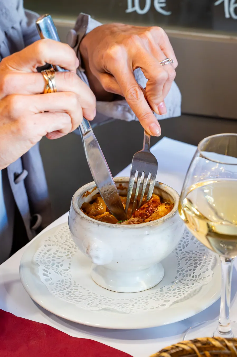 Hands digging into a gratinée lyonnaise