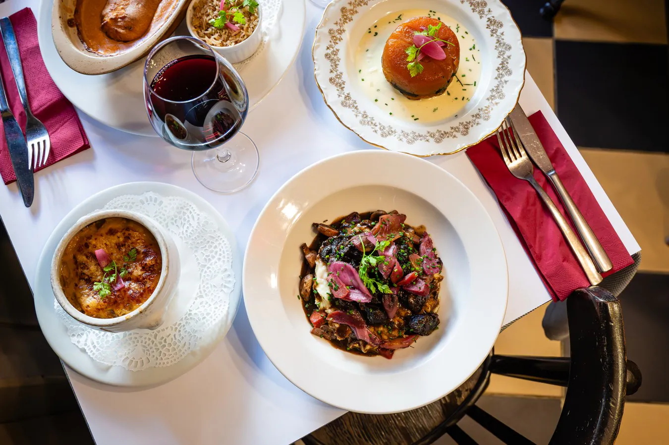A laid table seen from above: several dishes from the menu and a glass of red wine
