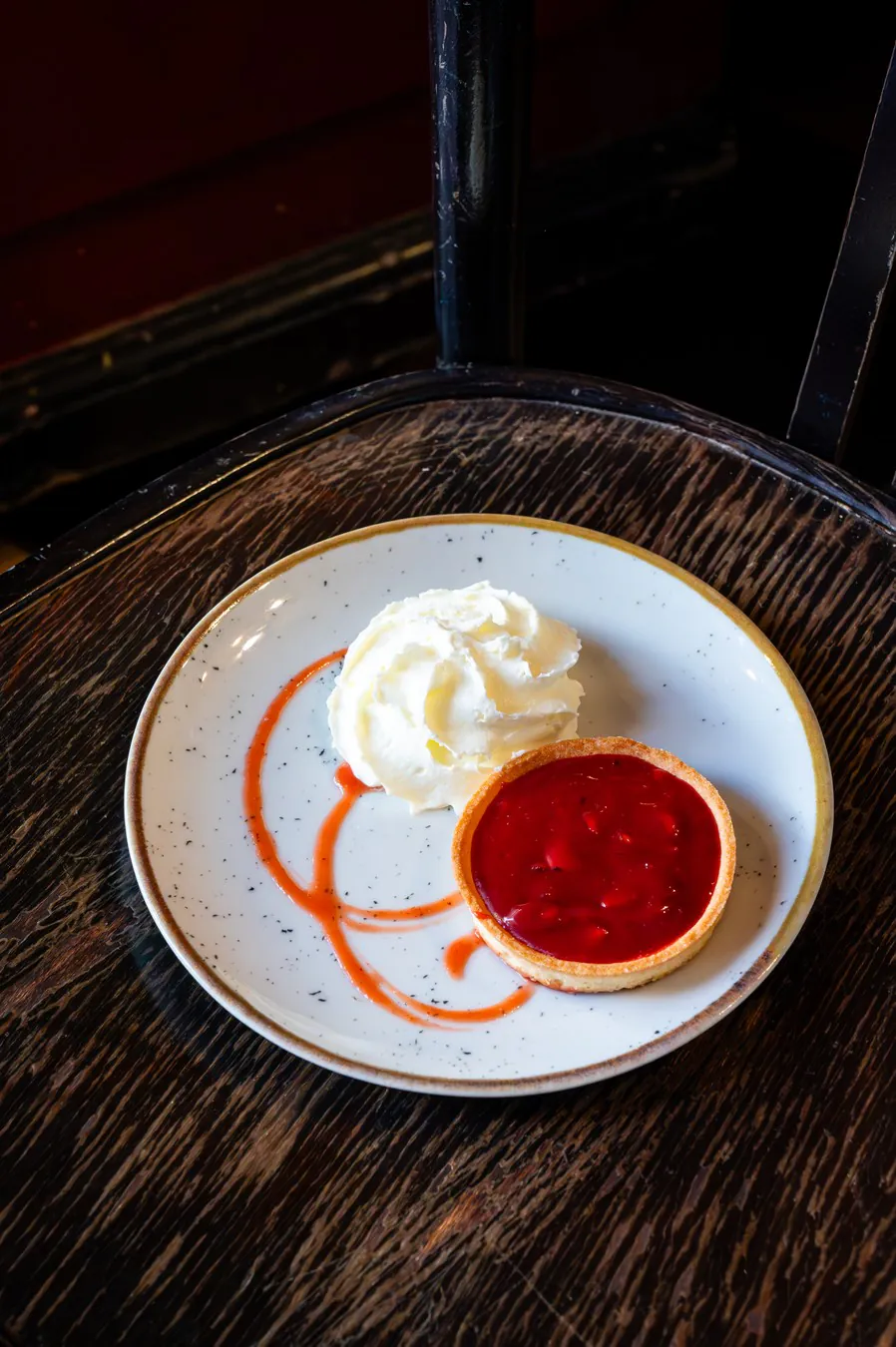 Pink praline tartlet and whipped cream, on a dark wooden table