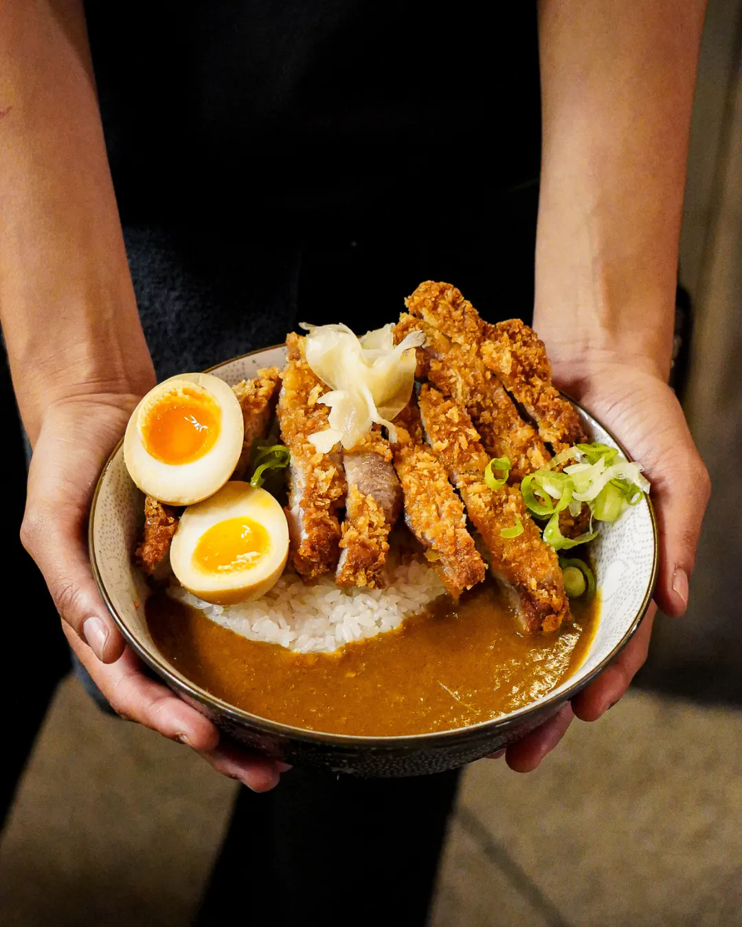 Bol de katsu curry tenu à deux mains dans la salle d'Iwao