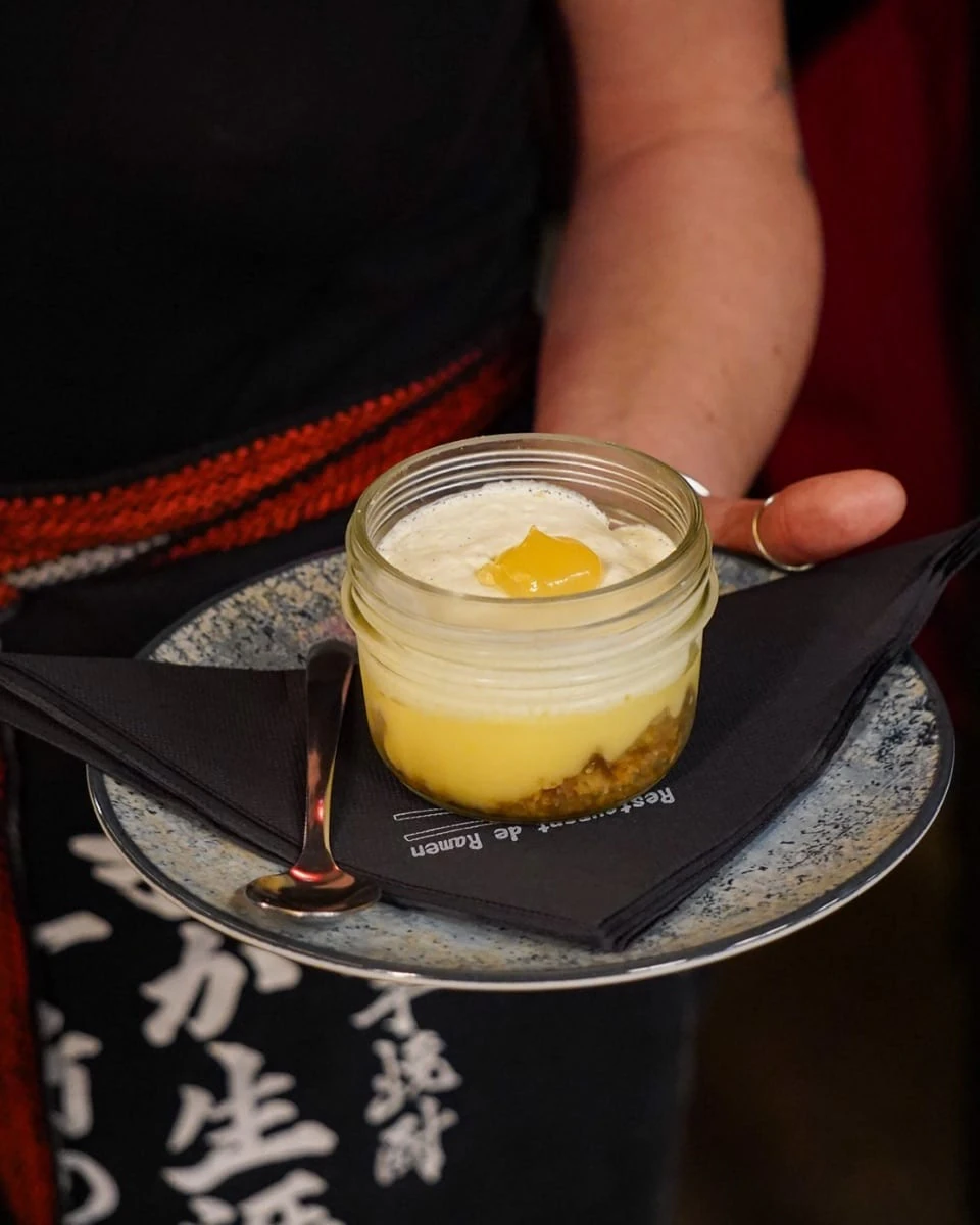 Server at Iwao restaurant in Marseille presenting a dish on a tray, open kitchen in the background