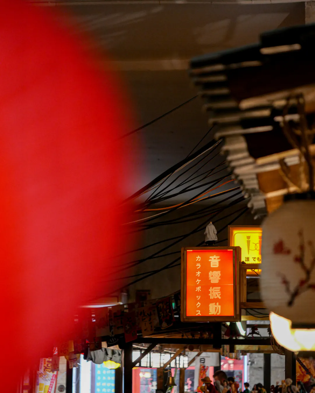 Ambiance nocturne d'Iwao : grand lampion rouge et enseigne karaoké lumineuse