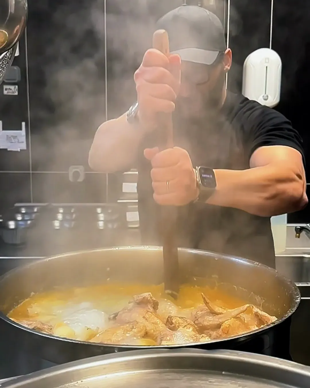 Cuisinier remuant un grand bouillon fumant dans la cuisine d'Iwao
