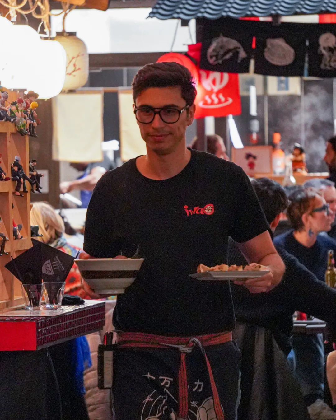 Serveur d'Iwao apportant un bol de ramen dans la salle