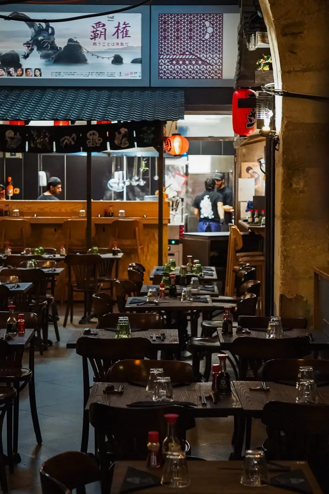 Salle du restaurant japonais Iwao à Marseille, tables dressées, cuisine ouverte et lanternes rouges