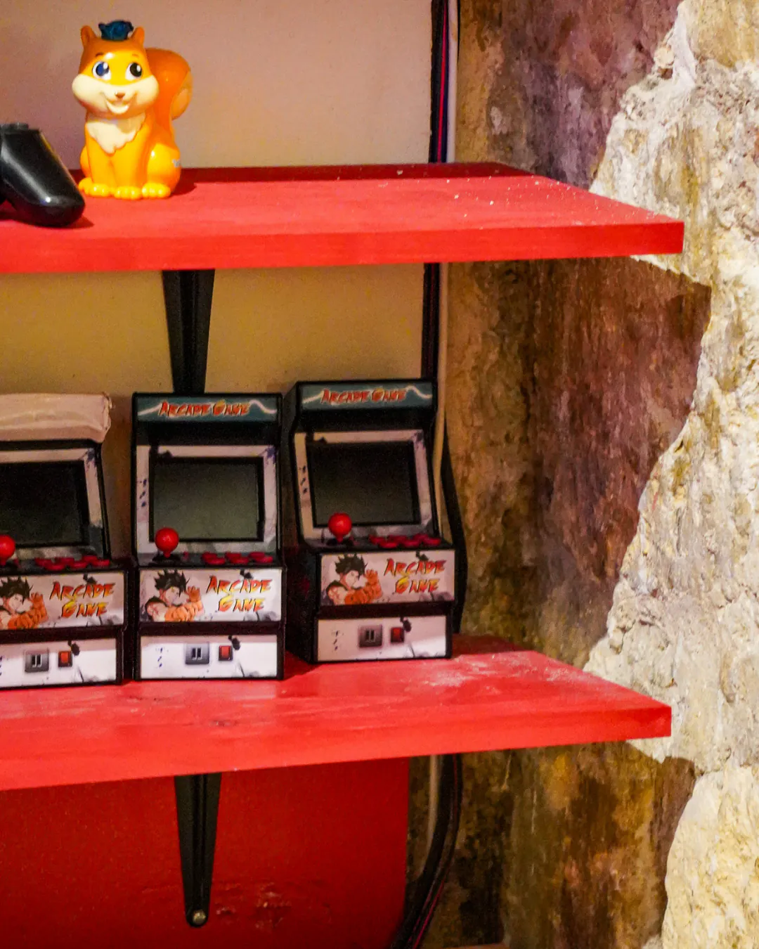 Étagères rouges d'Iwao avec mini-bornes d'arcade et manette de jeu