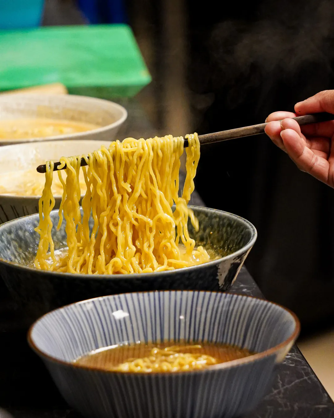 Baguettes soulevant des nouilles ramen fraîches en cuisine