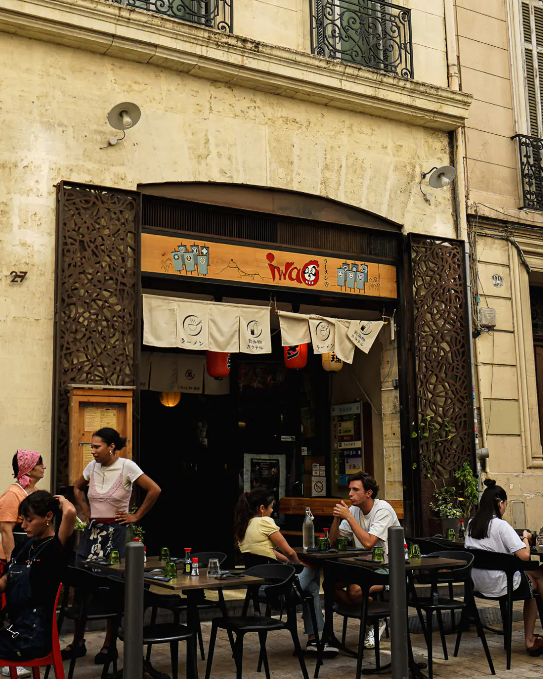 Façade et terrasse d'Iwao au 27 rue Sainte, enseigne daruma et noren