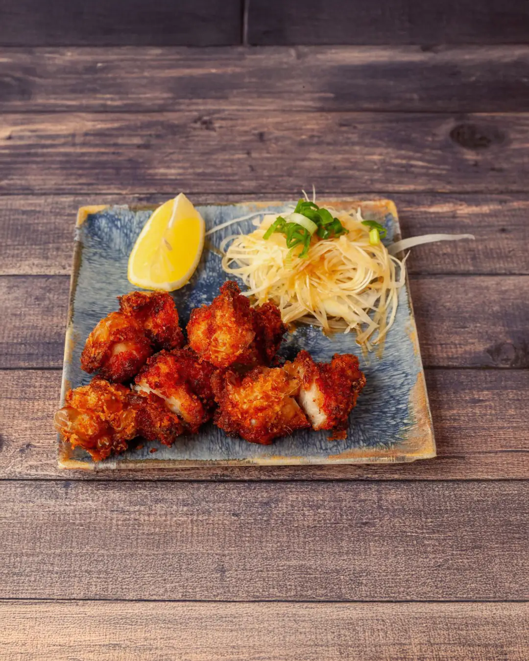 Poulet karaagé frit doré et quartier de citron sur assiette bleue