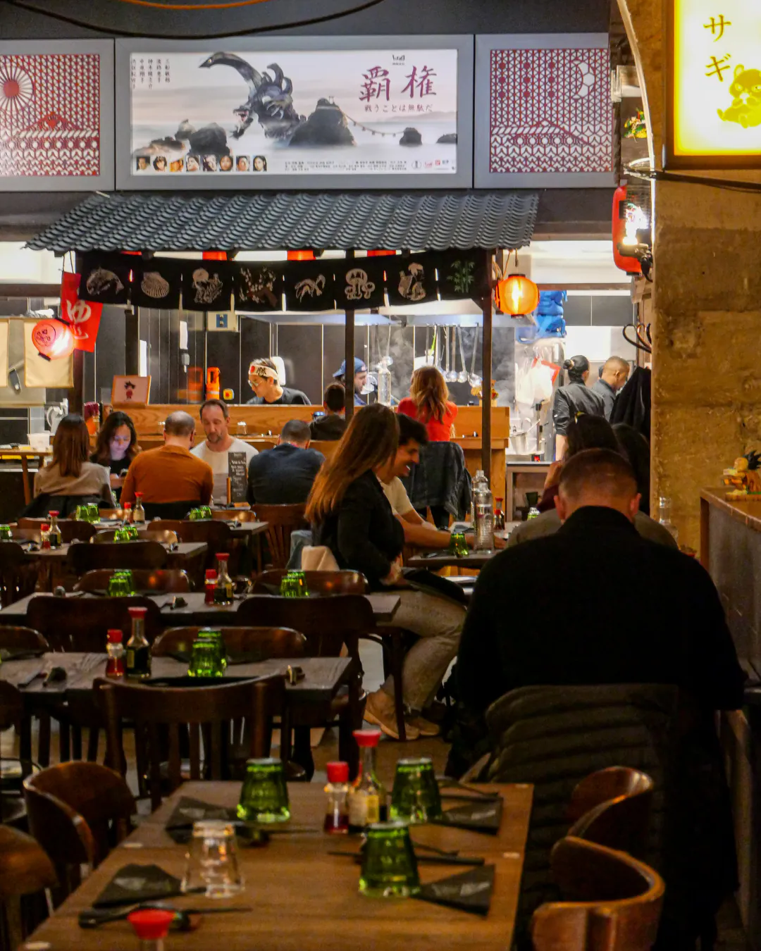 Salle animée d'Iwao avec cuisine ouverte et clients attablés le soir