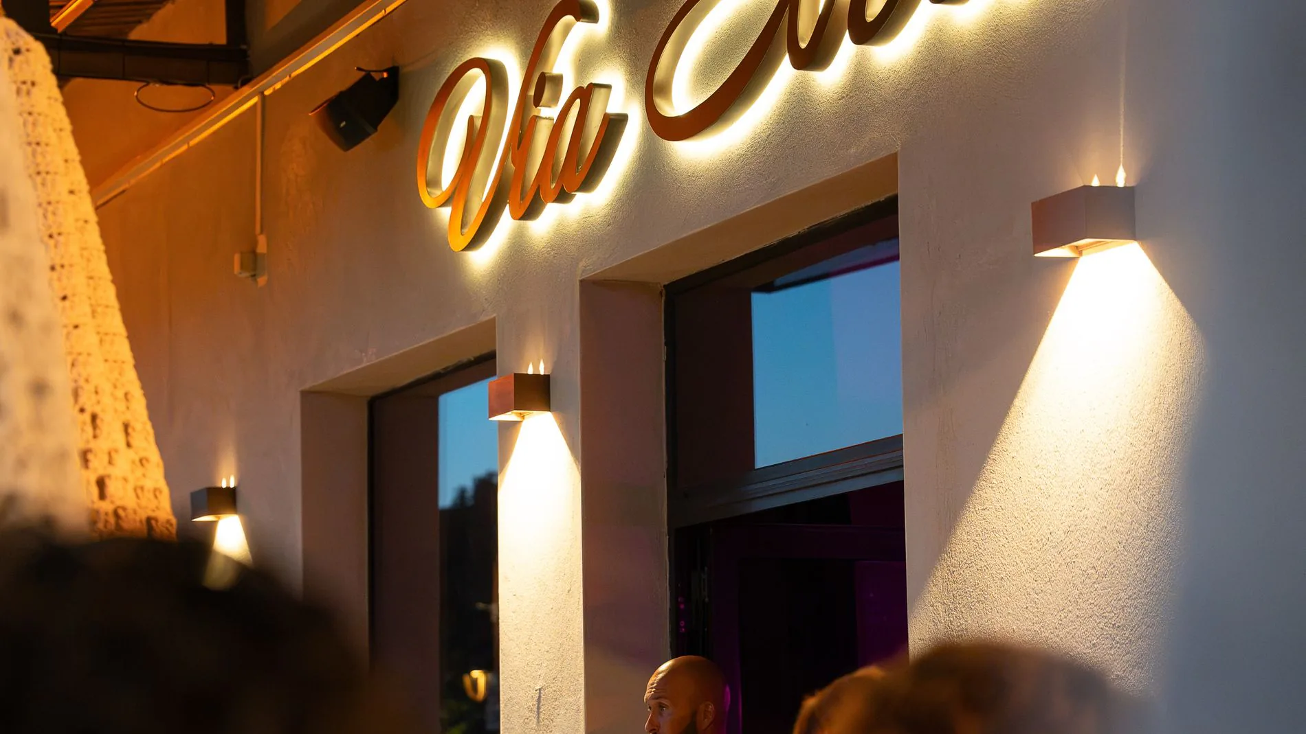 La façade éclairée du Via Notte le soir, enseigne lumineuse et clients à l'entrée
