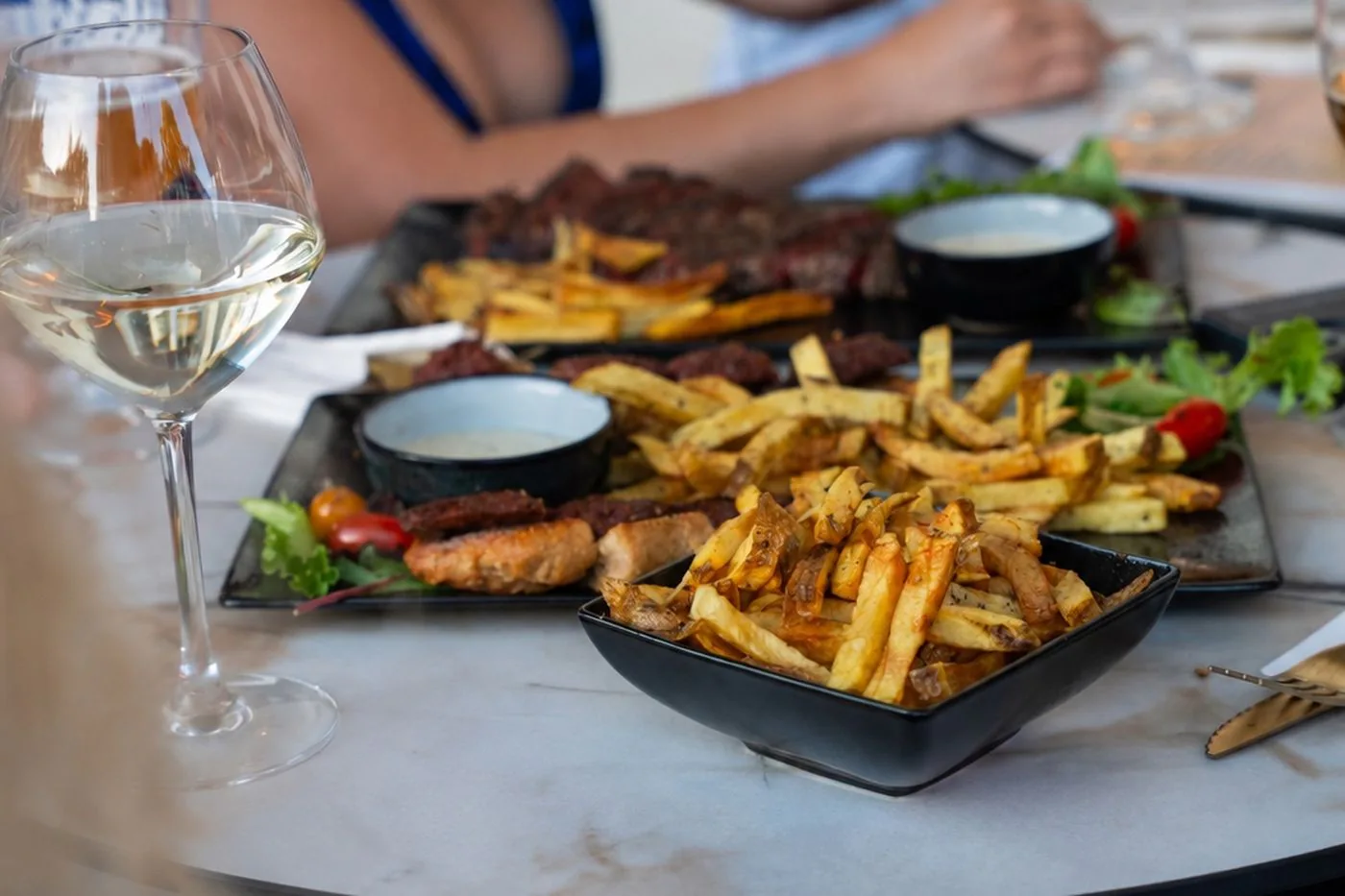 Table dressée avec planches, frites maison et vin blanc