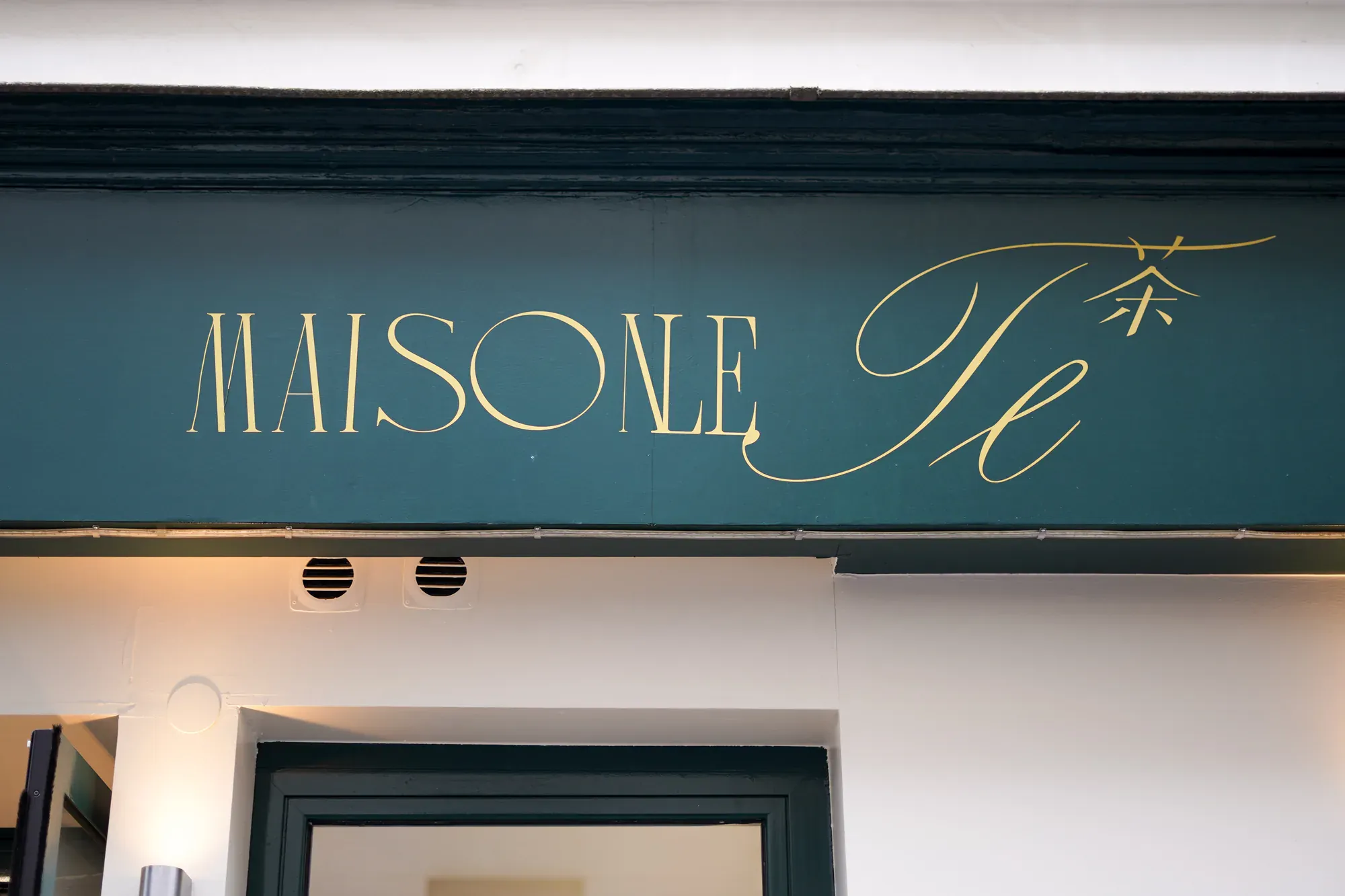 Enseigne dorée MAISON LE TÊ en lettres calligraphiées sur fond vert