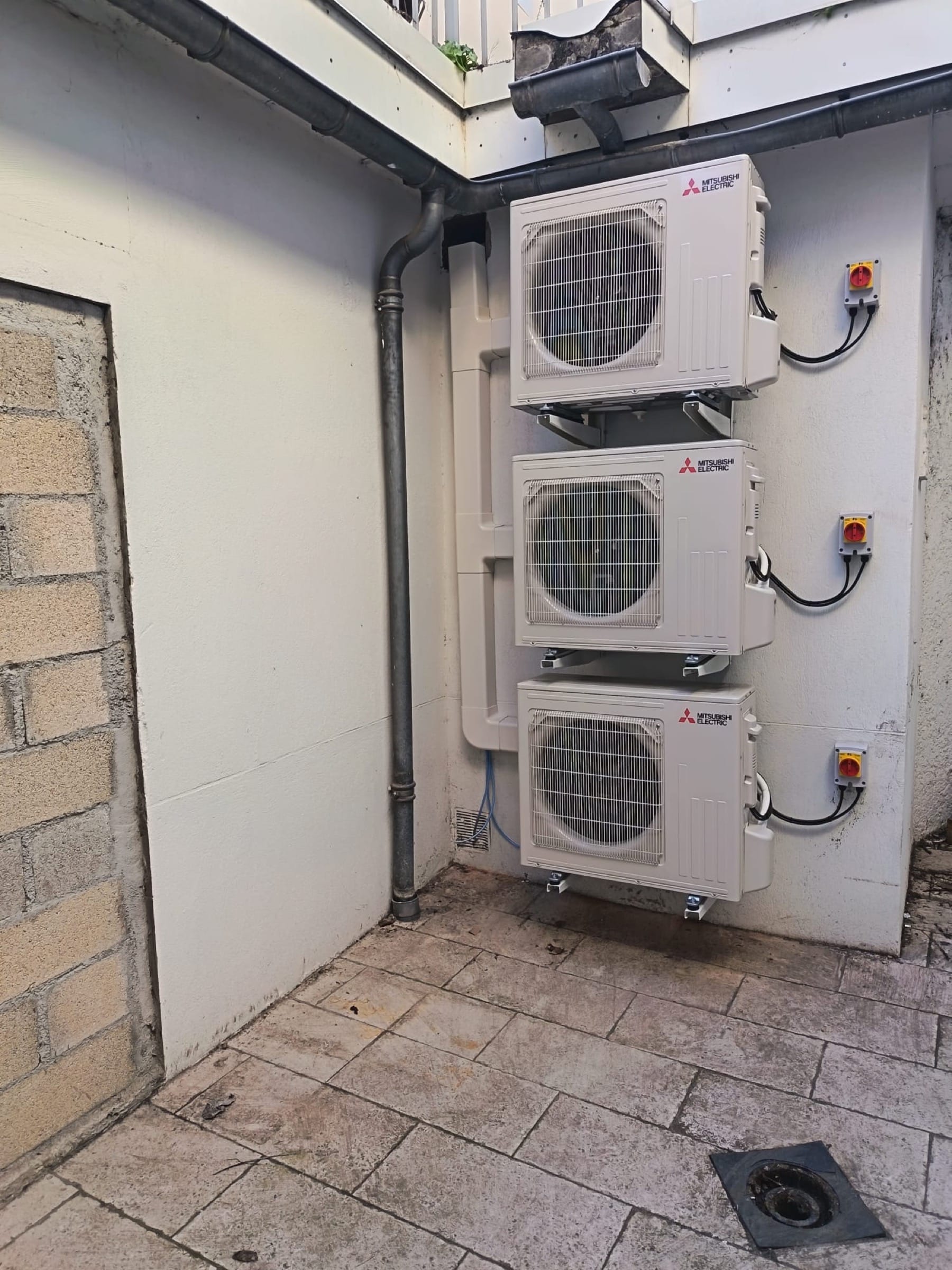 Trois unités extérieures de climatiseur Mitsubishi Electric installées en façade dans l'Albigeois