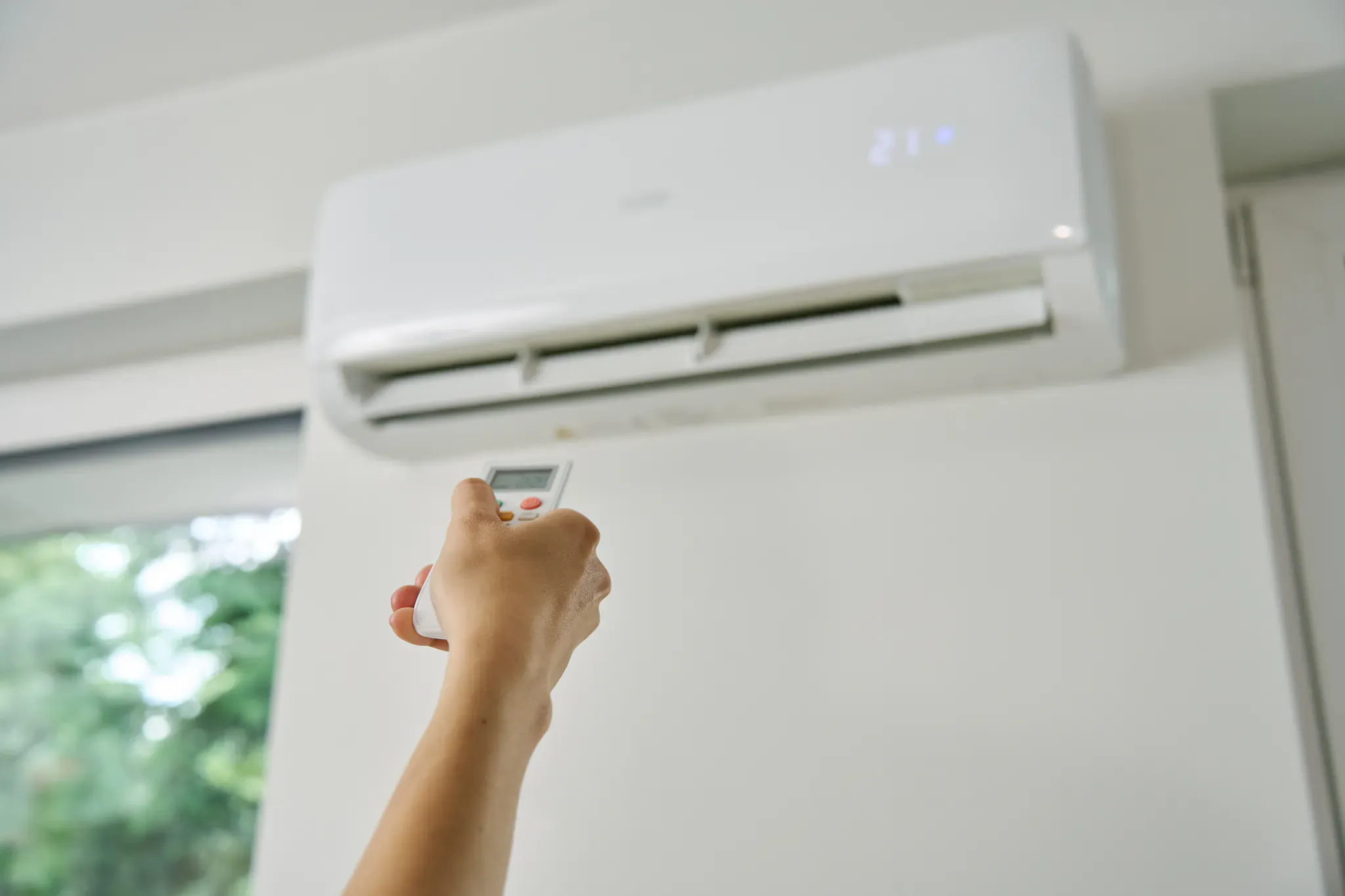 Réglage d'un climatiseur mural à 21°C avec la télécommande dans un intérieur à Albi