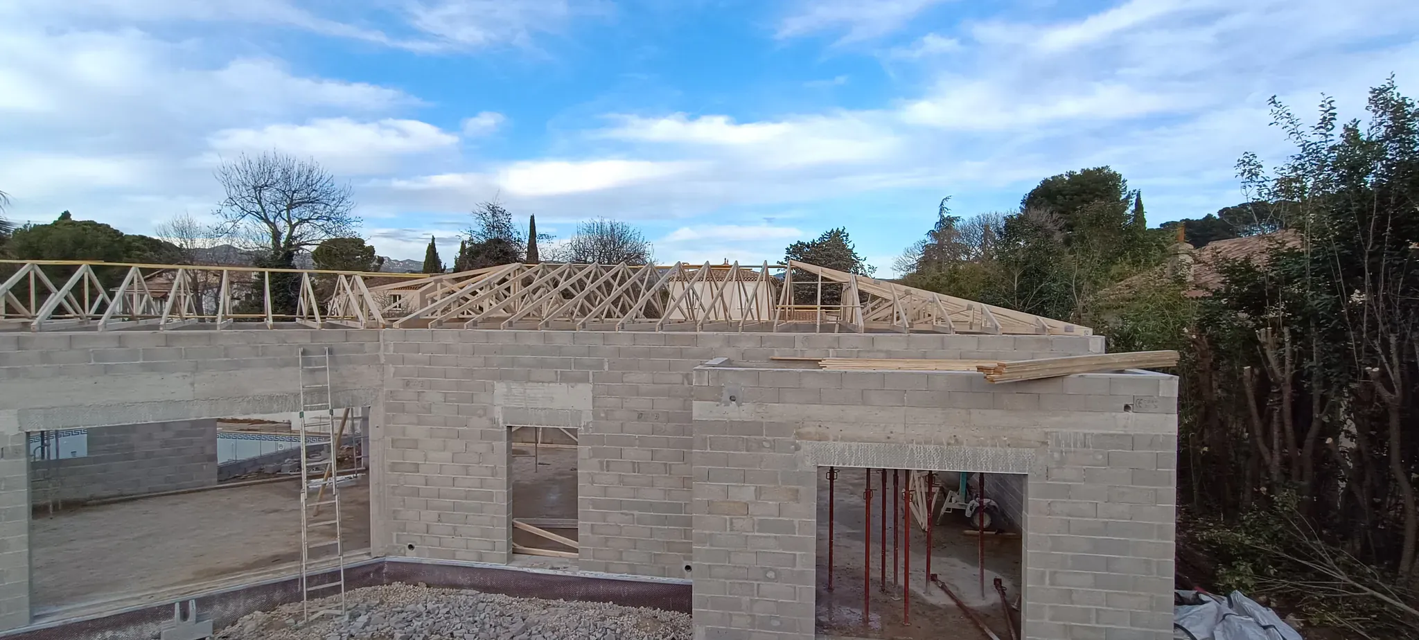 Maison en parpaings avec charpente en fermettes bois, chantier de construction en Provence
