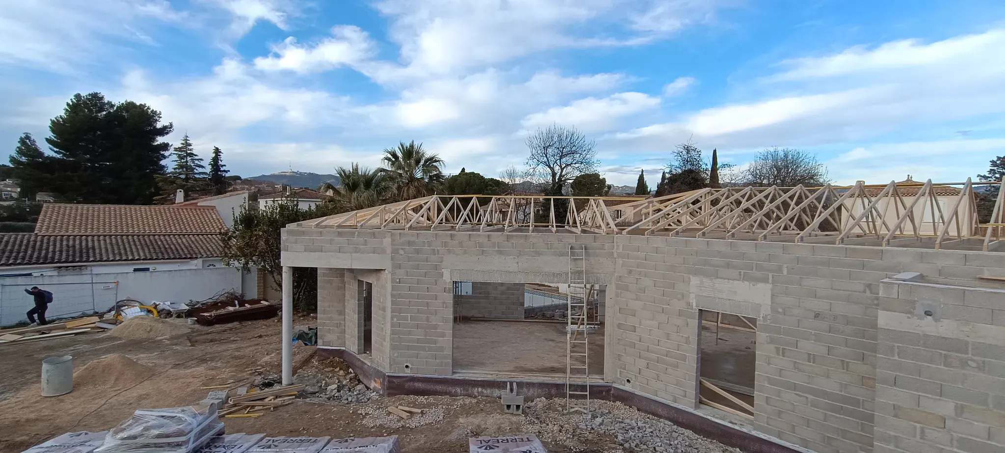 Maison individuelle en parpaings avec charpente bois posée, fondations terminées