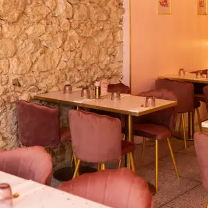 Salle en pierre apparente et chaises en velours rose