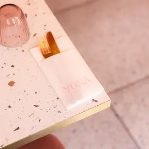 Serviette Yona et couverts dorés sur une table en terrazzo