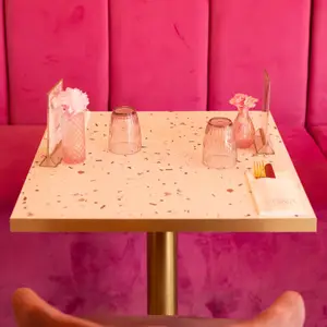 Table dressée devant la banquette rose, verres et fleurs
