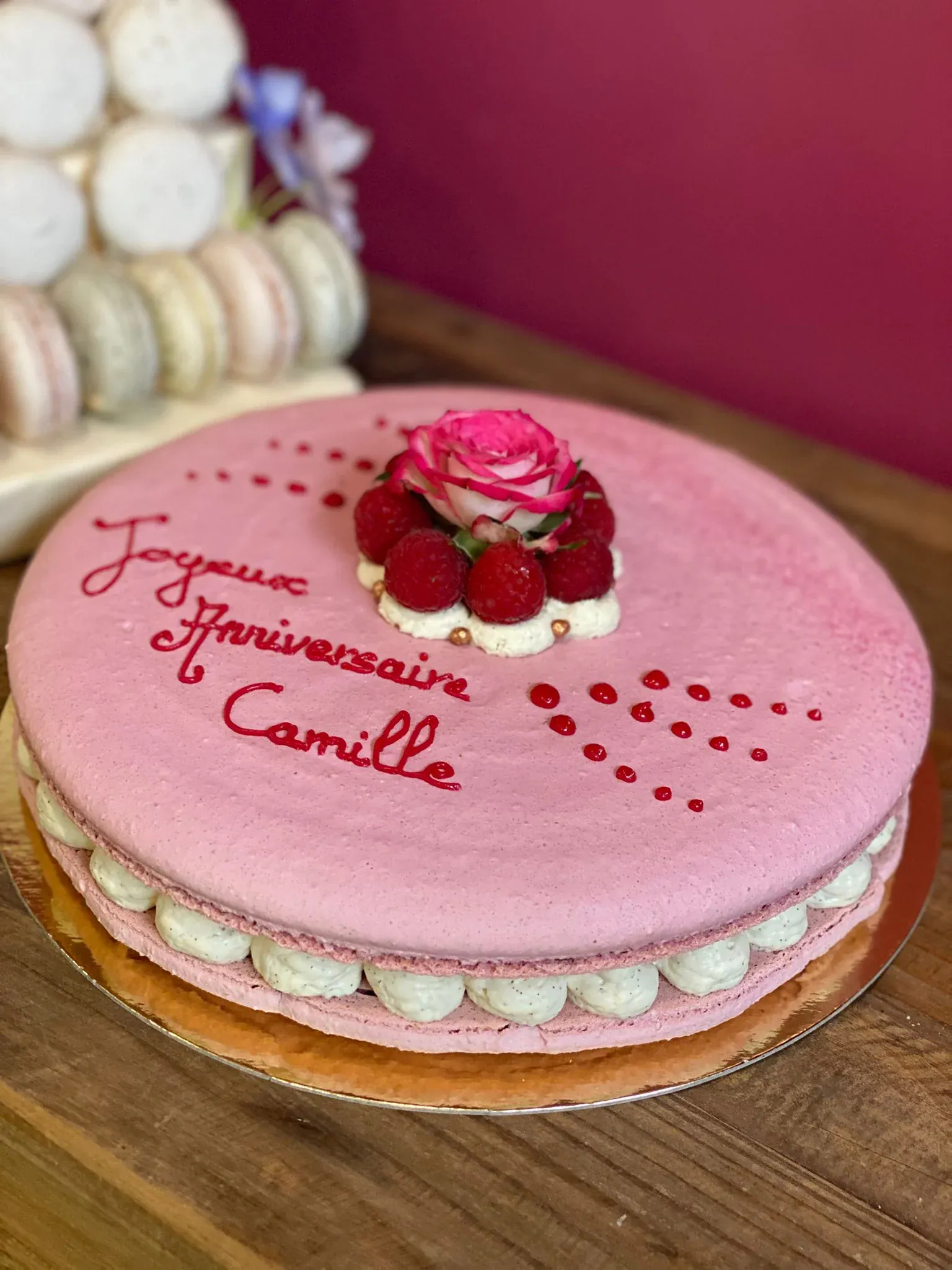 Grand macaron géant rose d'anniversaire surmonté d'une rose et de framboises, création événementielle