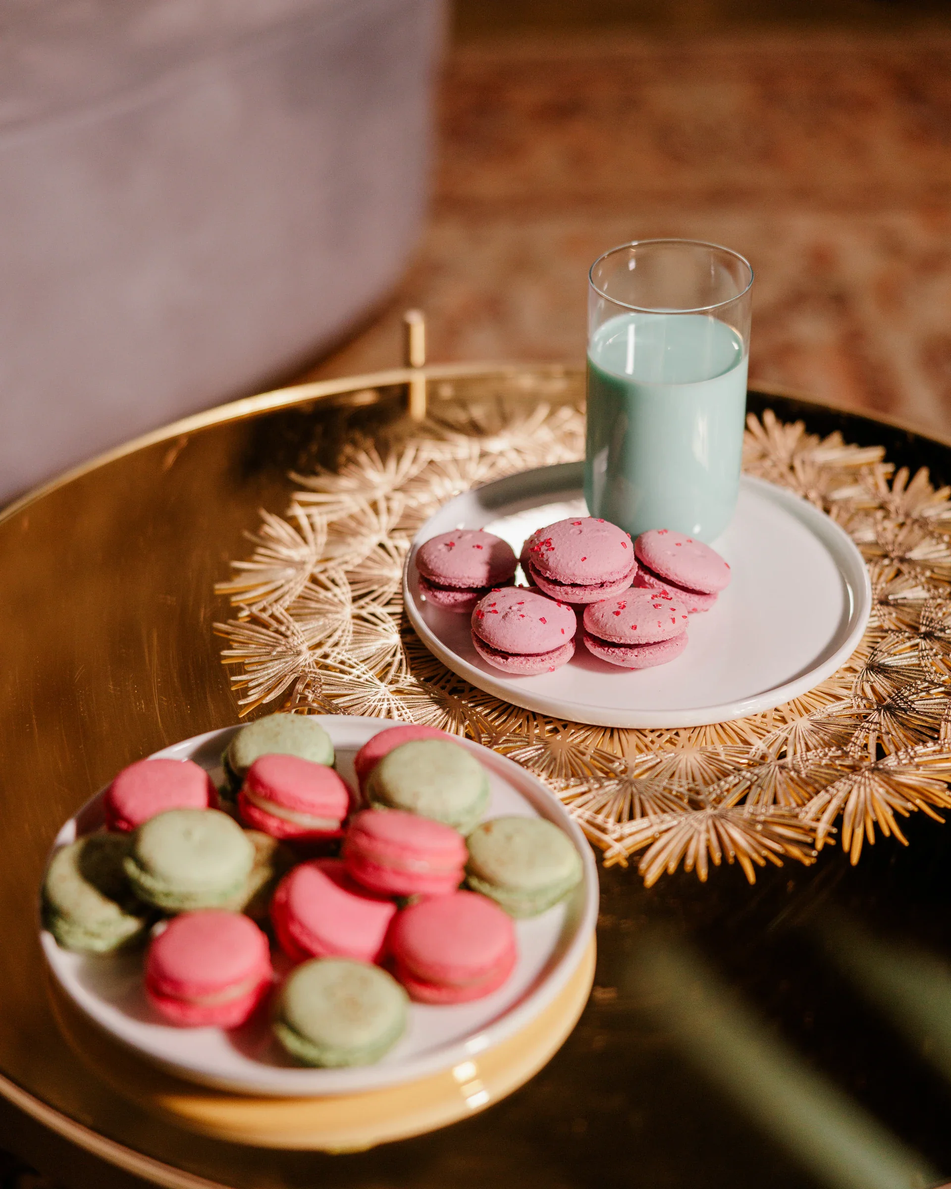 Deux assiettes de macarons roses et verts disposées sur un plateau doré, à partager entre plusieurs convives