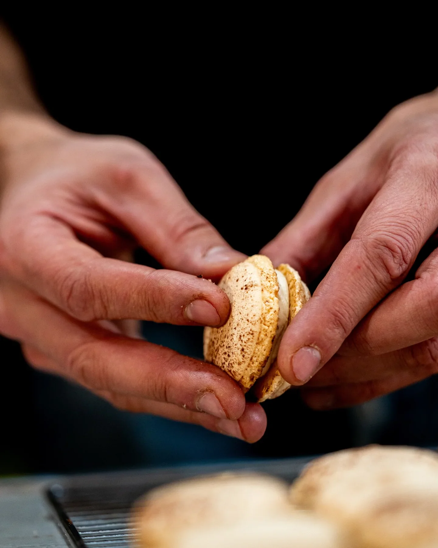 Mains du chef façonnant une coque de macaron à l’atelier