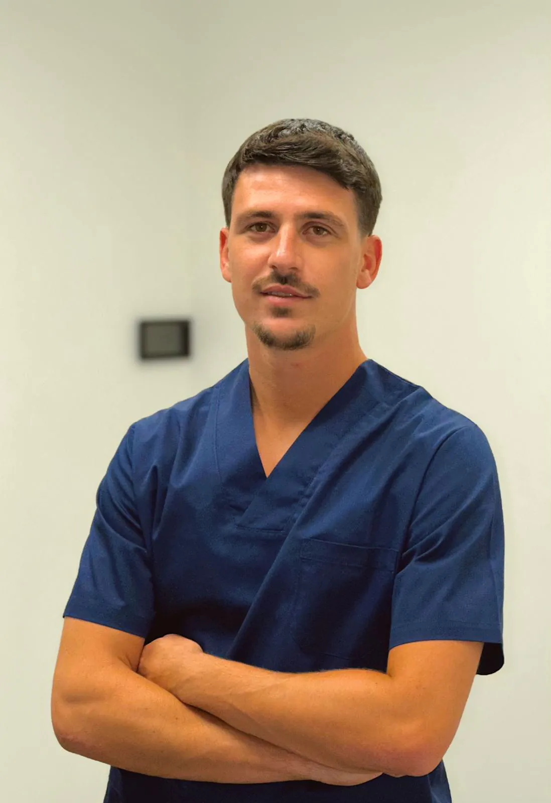 Portrait de Simon Baudoin, ostéopathe, en tenue médicale, bras croisés