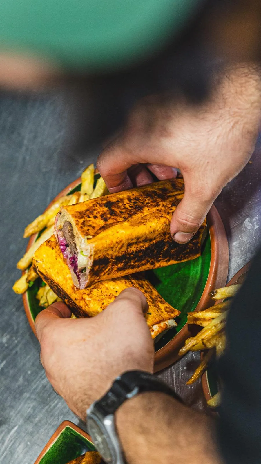 Un durum tenu à la main, coupé en deux et accompagné de frites maison