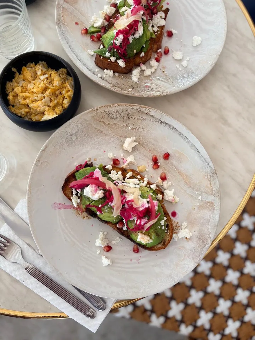 Deux avocado toasts à la feta et à la grenade, vus de haut sur une table de marbre