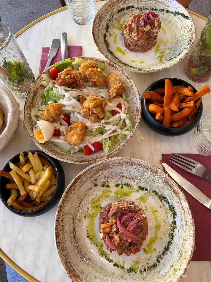 Une table servie vue de haut : tartares, poulet pané, frites de patate douce