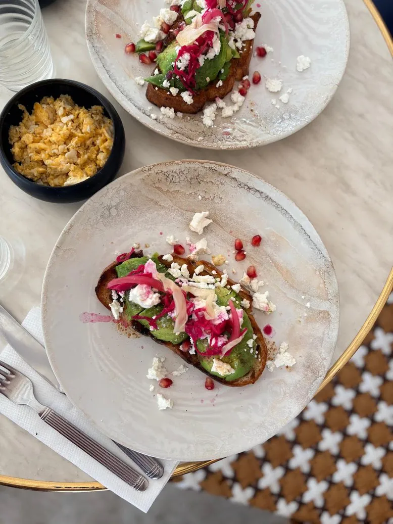 Deux avocado toasts à la feta et à la grenade, vus de haut sur une table de marbre