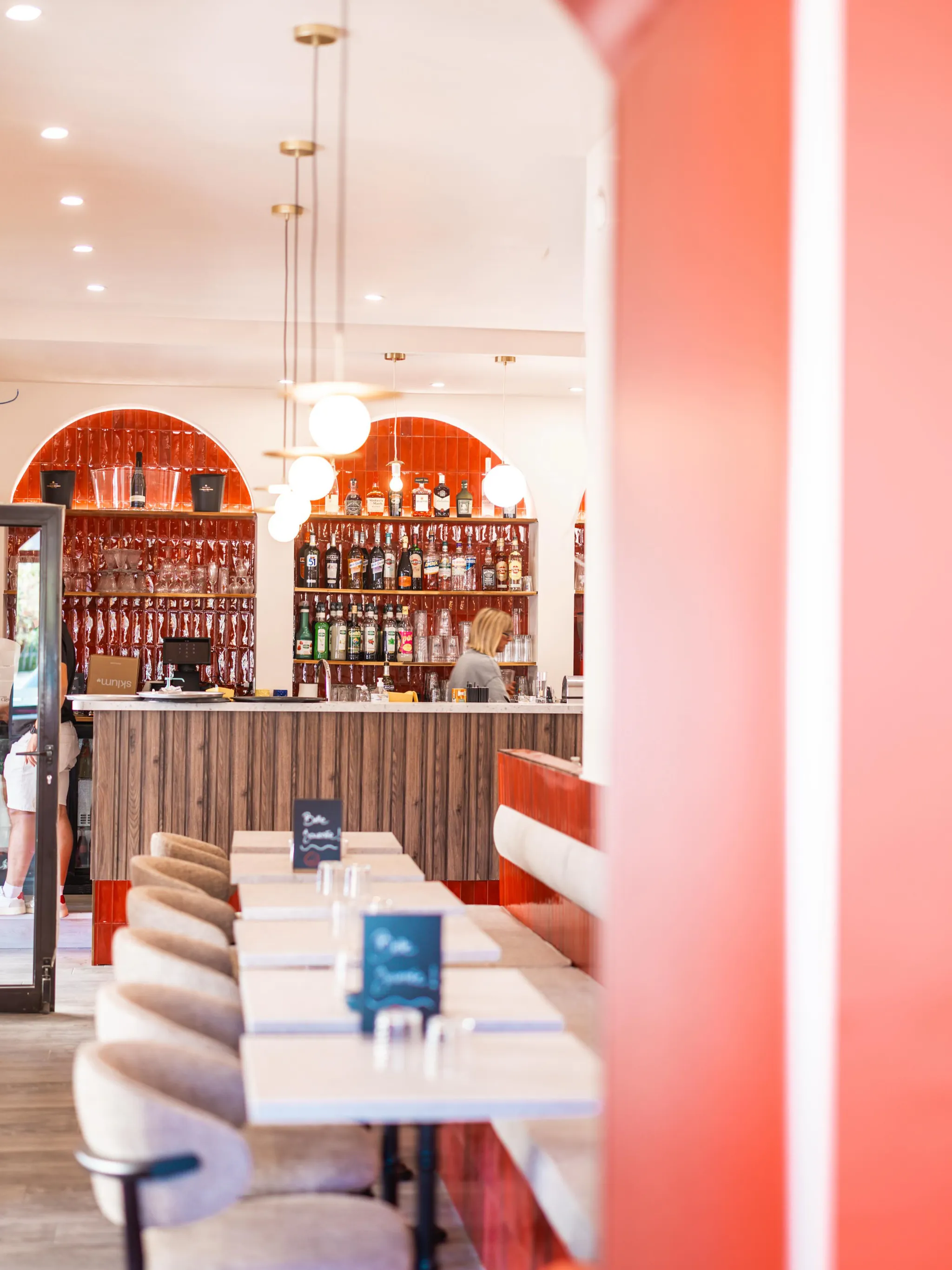 La salle du Petit Rouet : trois arches de faïence rouge, le comptoir en bois clair et ses globes opalins