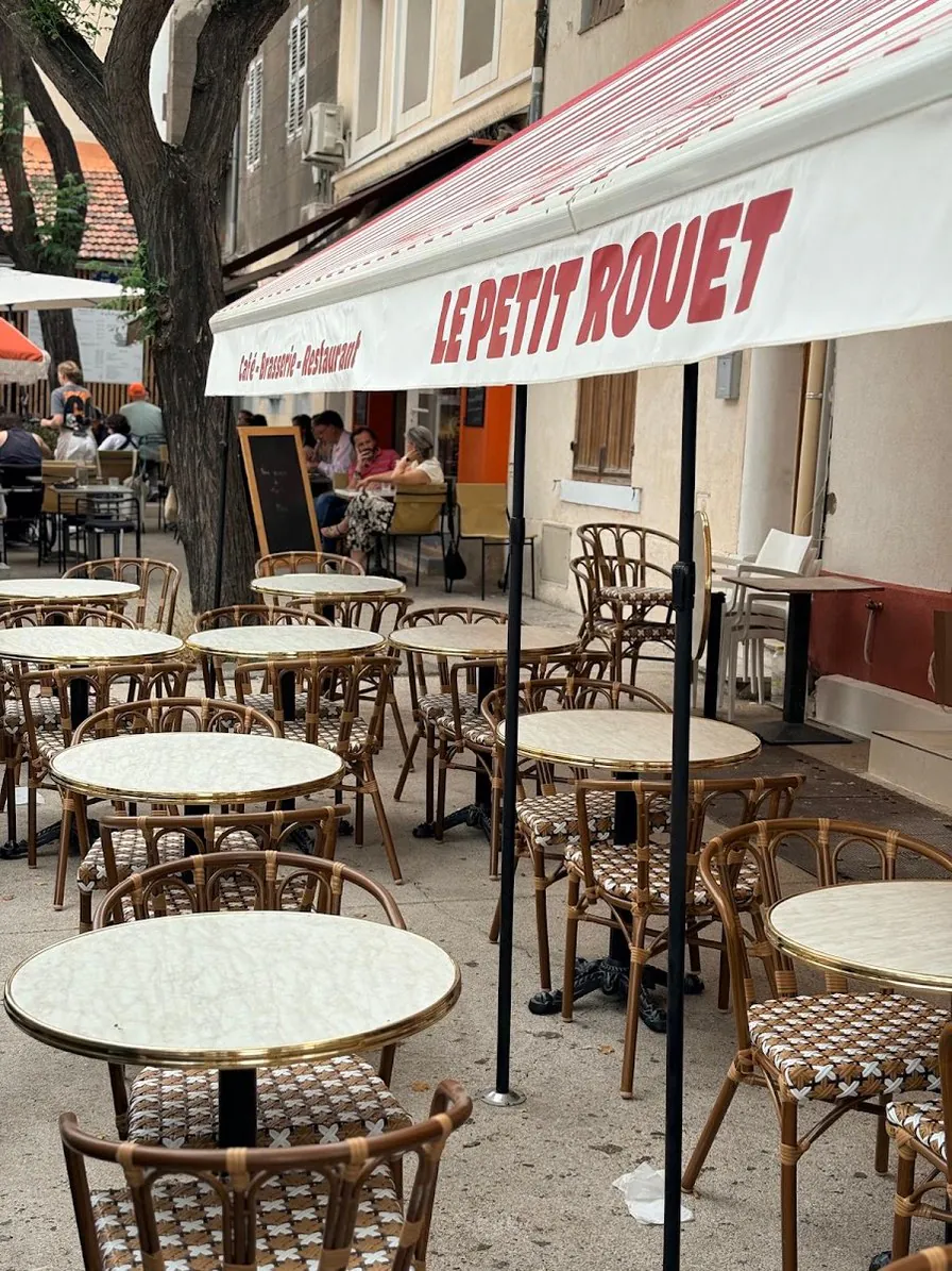 La terrasse sous le store rayé rouge et blanc lettré Le Petit Rouet