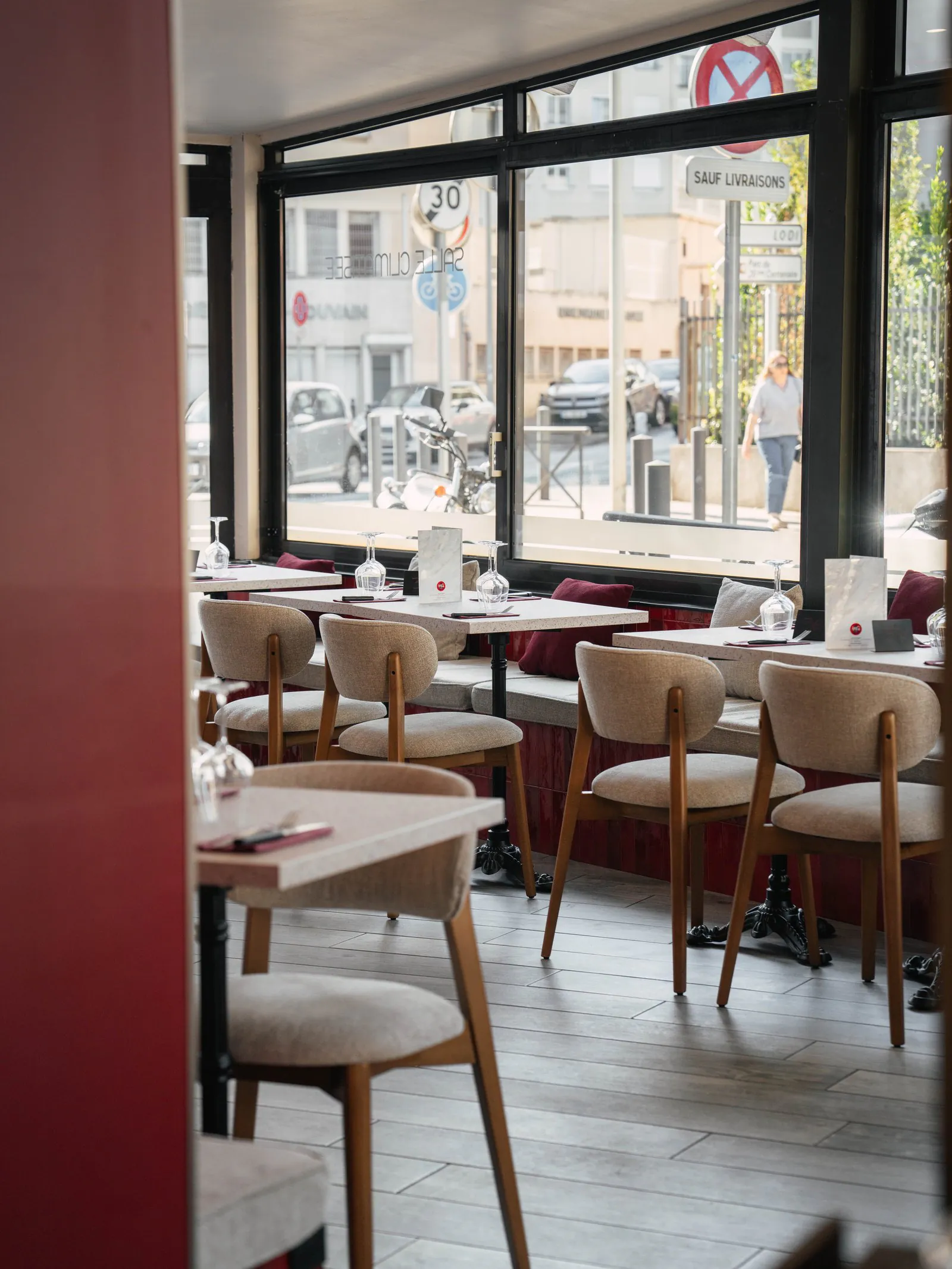 La salle du Petit Rouet le long de ses grandes baies vitrées, tables dressées et chaises claires