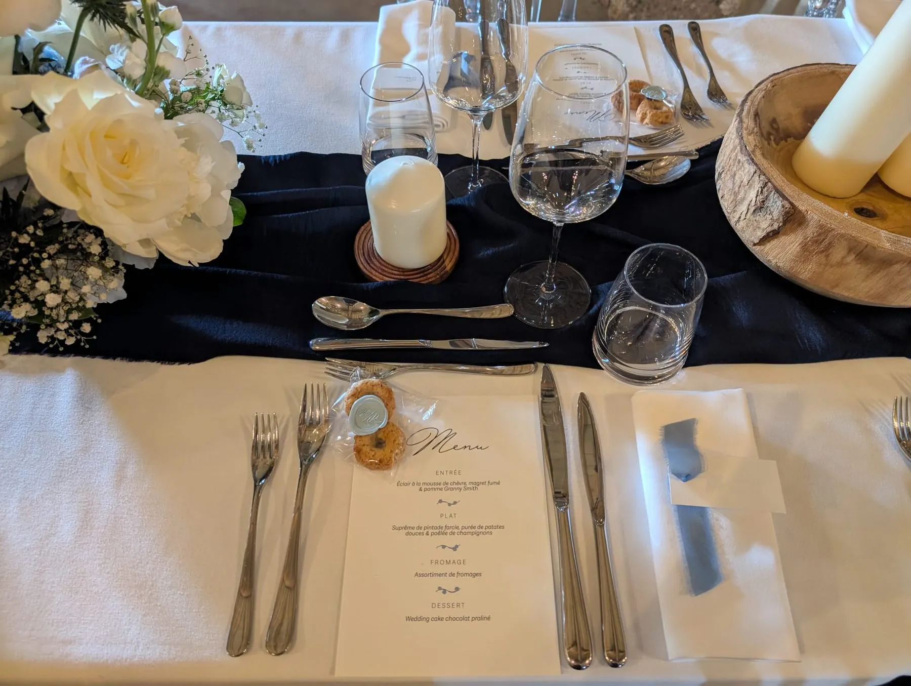 Table de mariage dressée : roses blanches, bougies et chemin de table bleu nuit