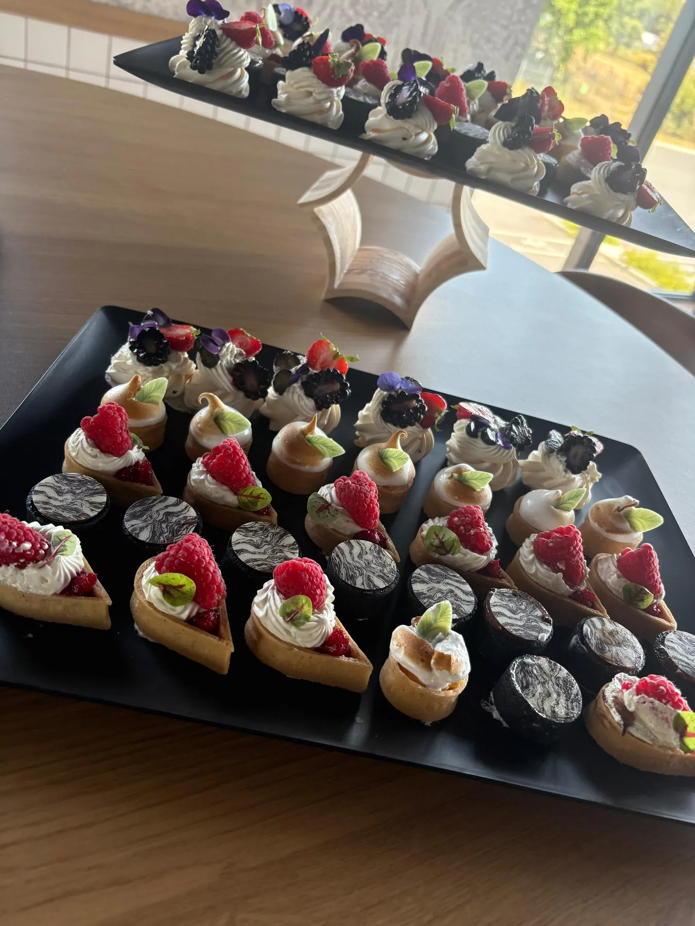 Plateaux noirs de mignardises : mini-tartelettes aux framboises, meringues et pavlovas