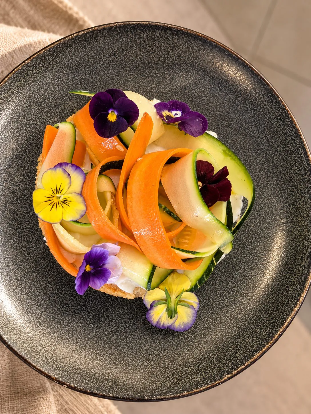 Tartelette de légumes vue du dessus, rubans de carotte et de courgette, fleurs comestibles