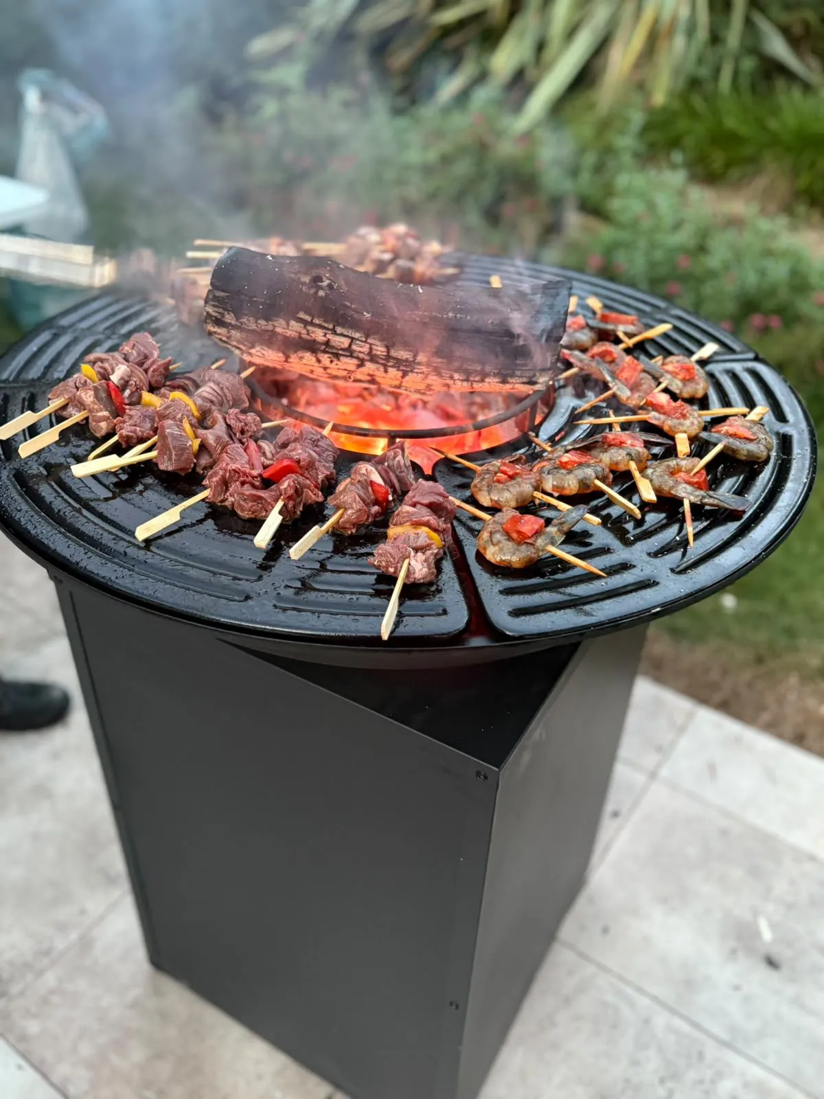 Brasero-plancha en extérieur avec brochettes de bœuf et de crevettes en cours de cuisson