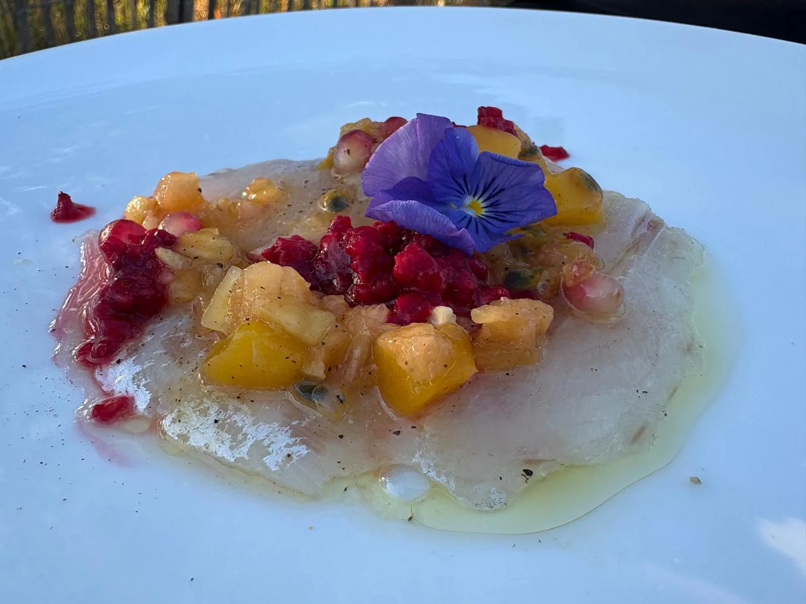 Carpaccio de poisson blanc à l’huile d’olive, dés de mangue, grenade et fleur comestible, en entrée de mariage
