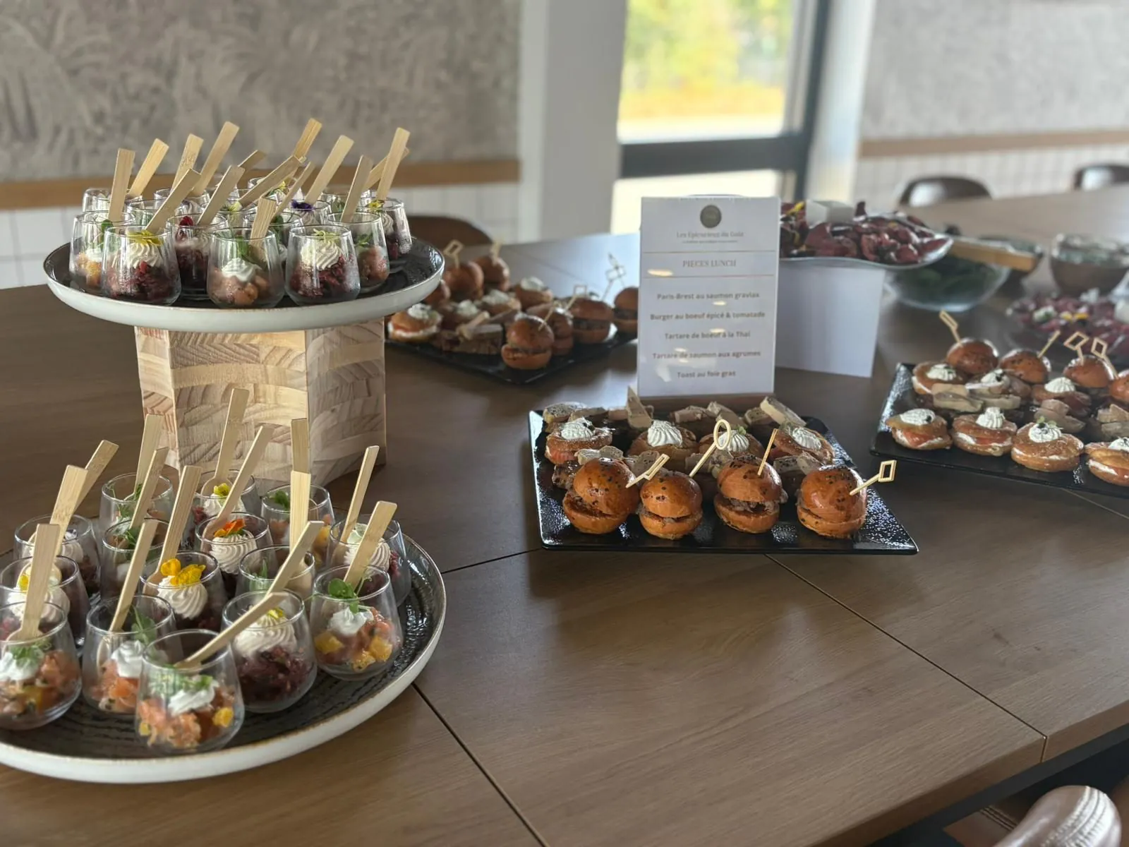 Buffet de pièces cocktail sur table en bois avec verrines sur présentoirs et mini-burgers