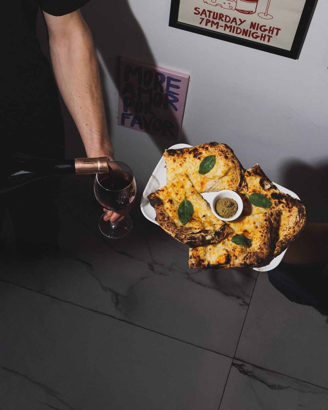 Table dressée chez Di Micheli avec une pizza artisanale et un verre de vin rouge servi