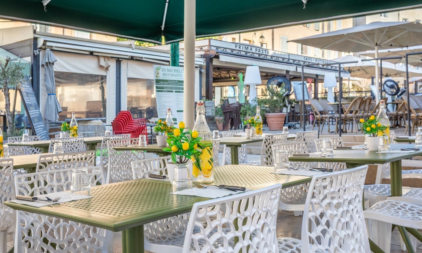 Terrasse dressée avec tables vertes et chaises blanches devant le restaurant italien Di Micheli à Aix-en-Provence