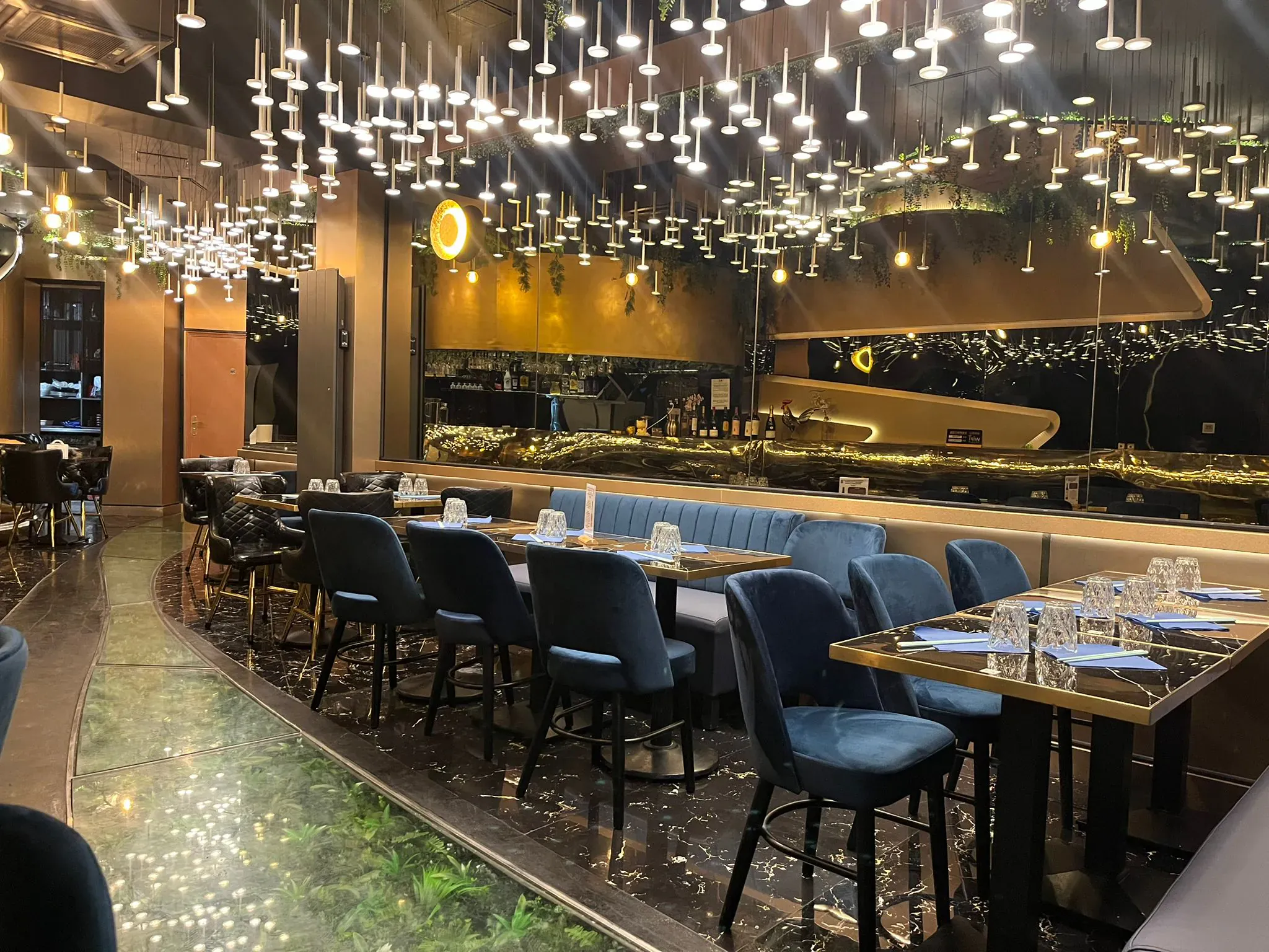 Banquettes en velours bleu nuit et cascade de suspensions cristal du salon Phở 98