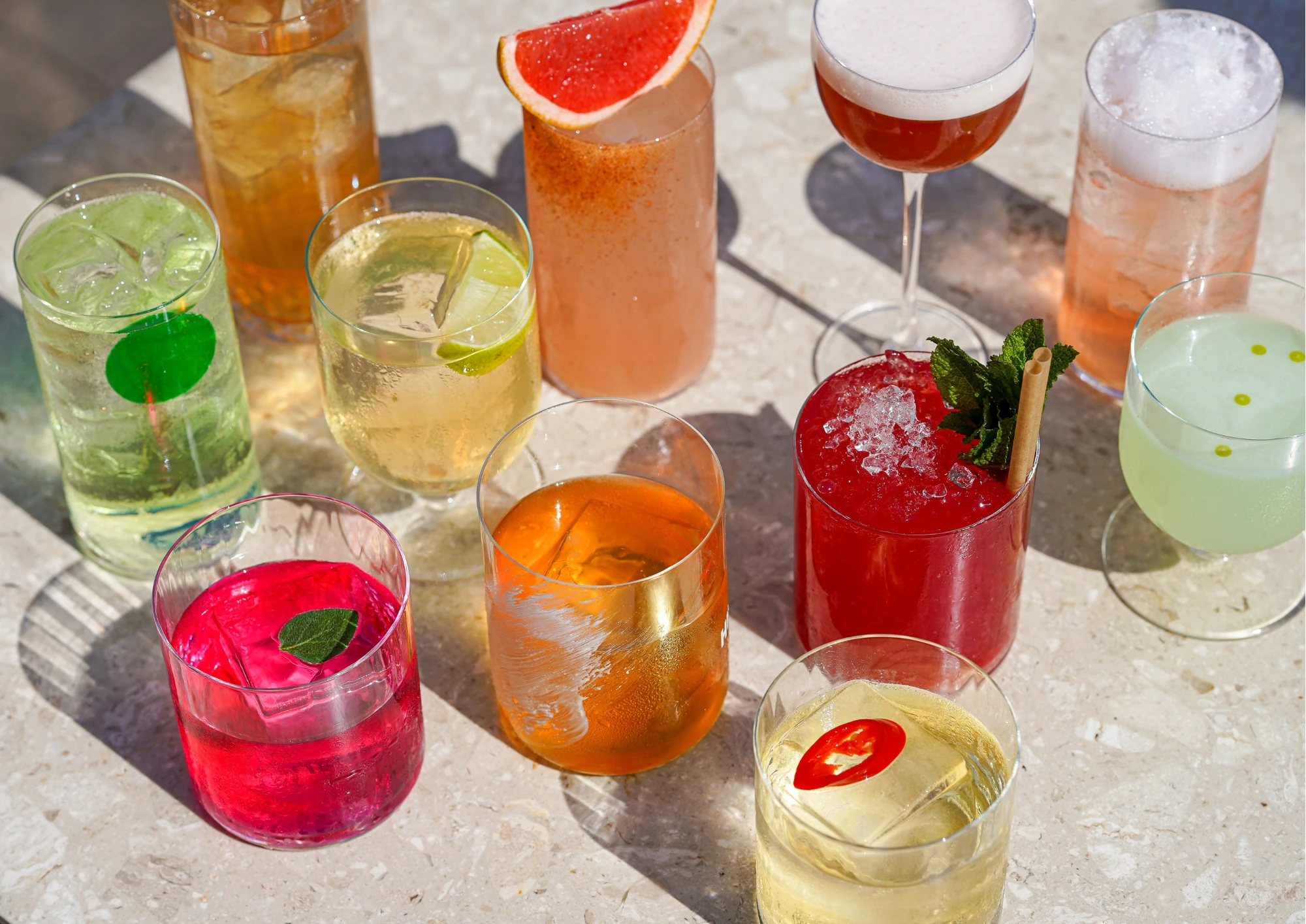 Assortiment de cocktails colorés dressés sur une surface claire au bar du Caribou.
